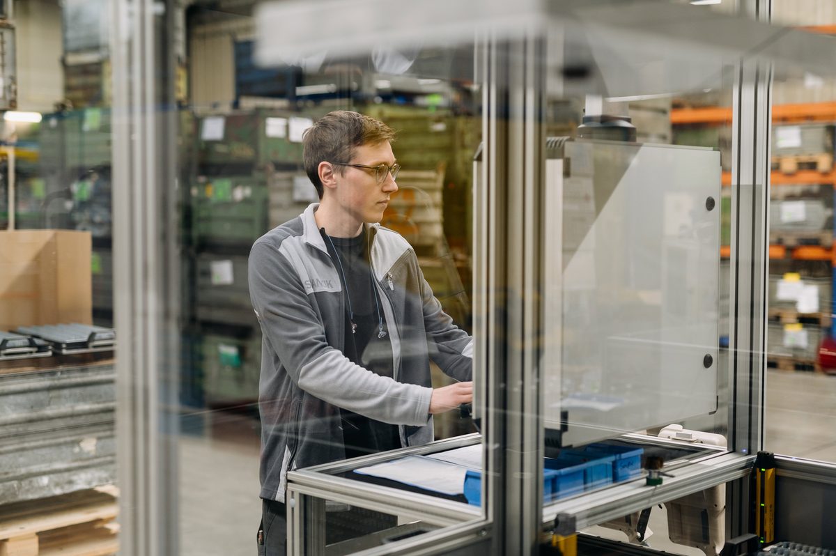 Mitarbeiter bedient eine Automationszelle mit Schutzeinhausung