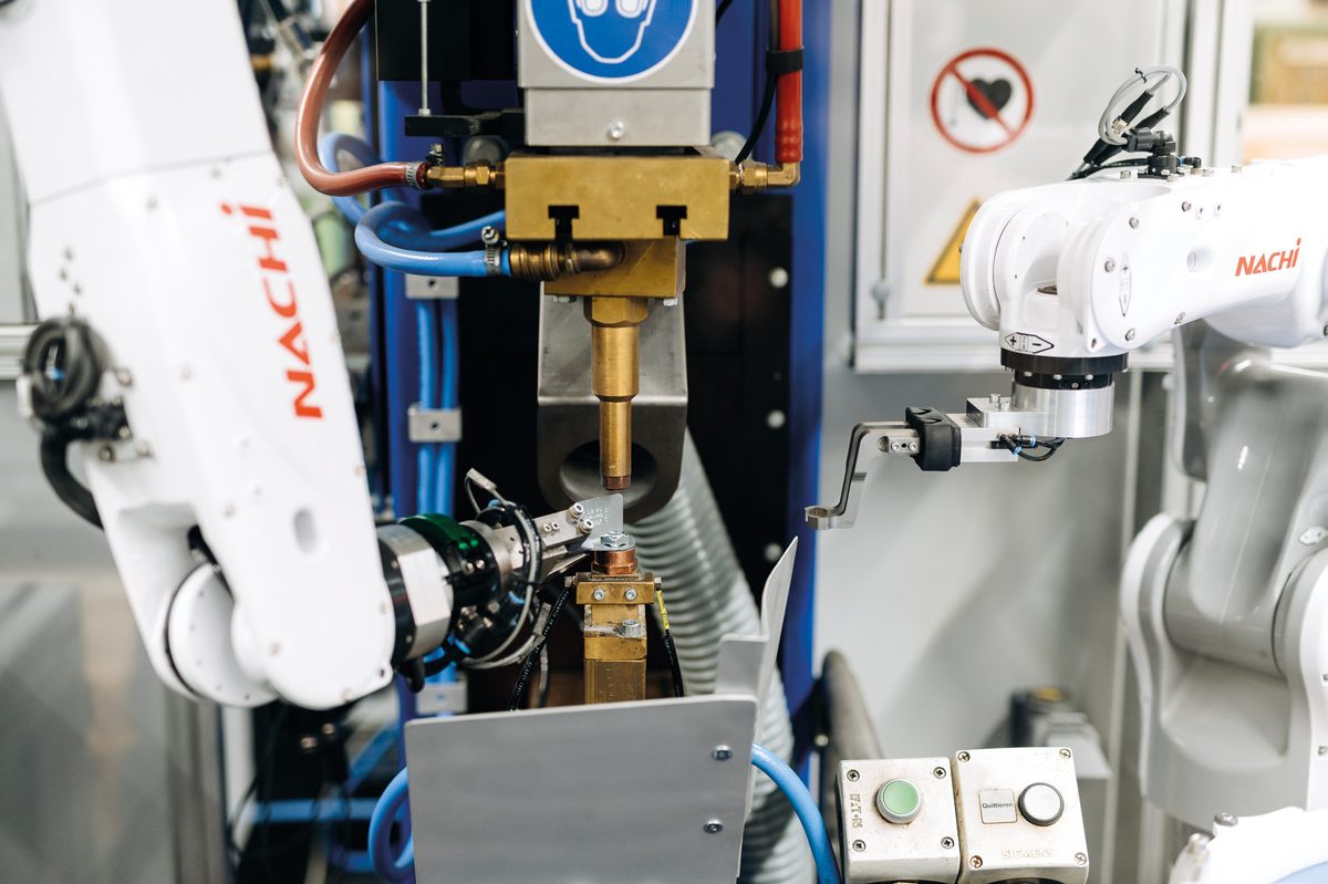 Zwei weiße Industrieroboter mit Schweißbrennern in einer Anlage
