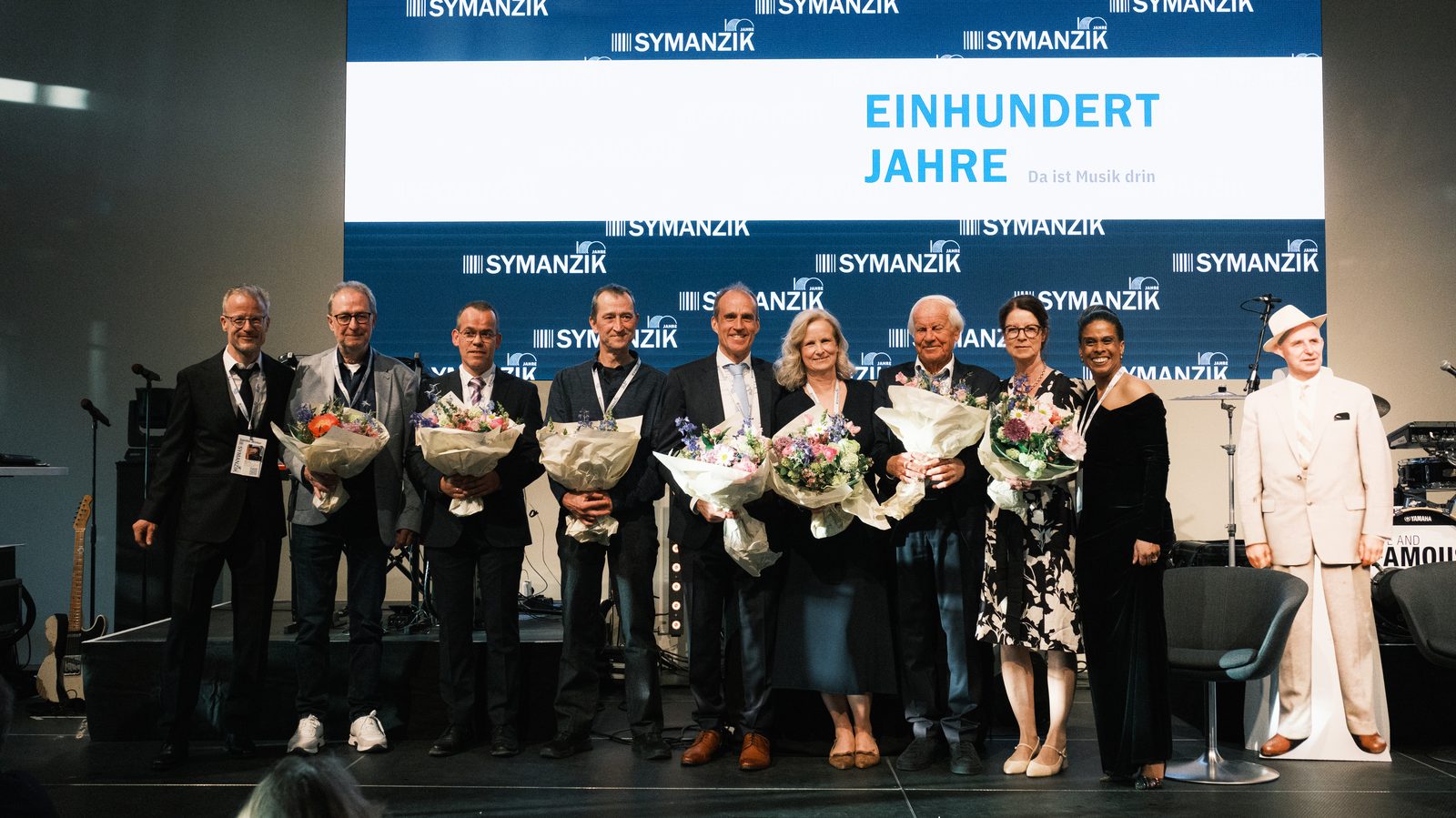 Gruppenbild auf der Bühne der 100-Jahr-Feier vor dem Schriftzug Einhundert Jahre, 2. Mai 2026