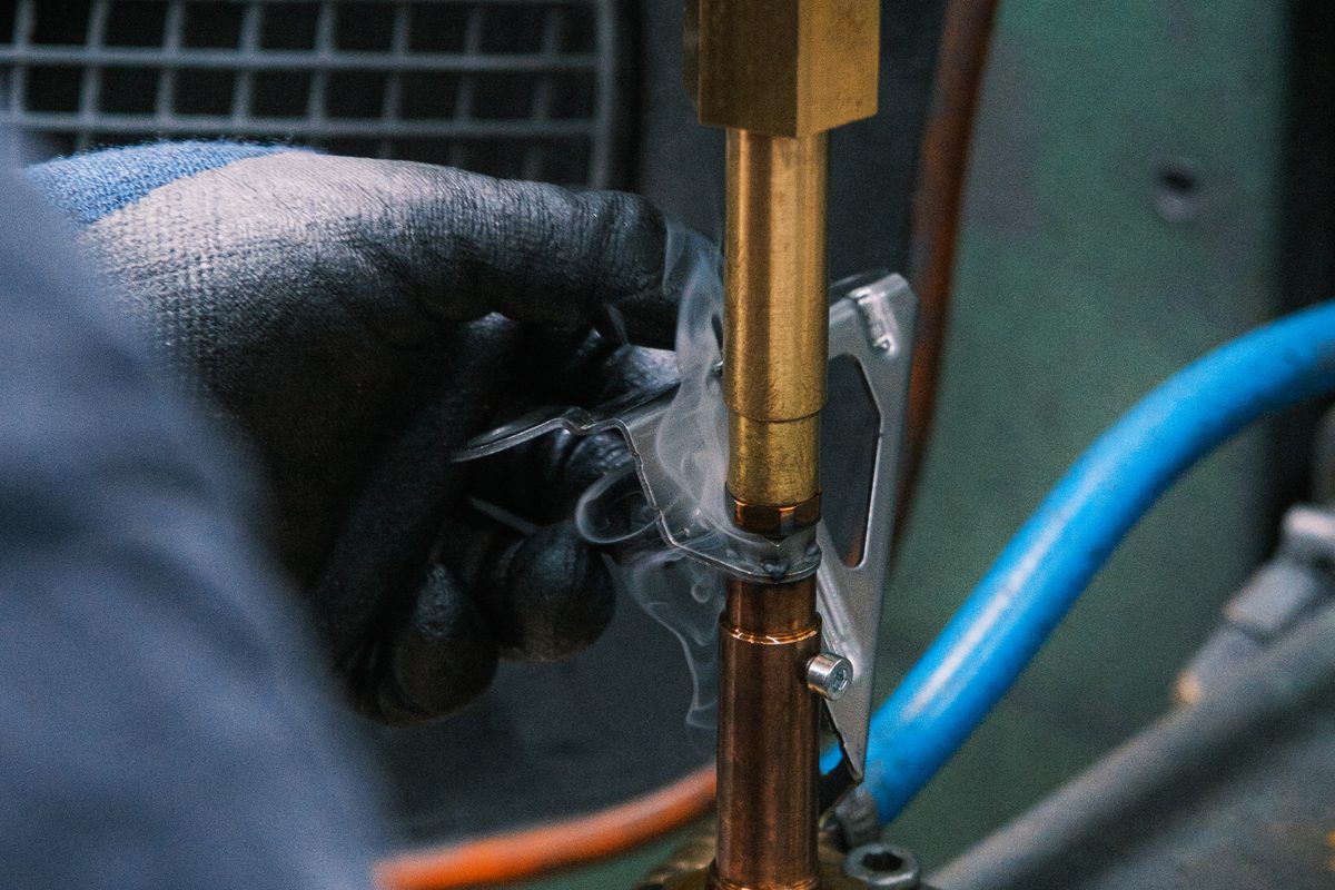 Mitarbeiter legt ein Bauteil in eine Schweißmaschine ein